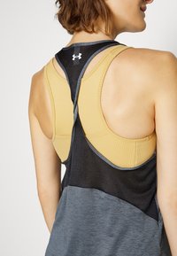 Idrottslig linne med en dubbel-lagerdesign som har en gul ribbad övre del och en svart mesh-lowersektion, accentuerad med grå sömnadsdetaljer.