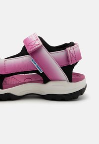 Pink and black water-friendly sandal with Velcro straps, a textured upper, cushioned insole, and a rugged black outsole.