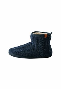Zapatilla de punto azul marino con un patrón de cable, suave forro de felpa y una suela de goma negra. Presenta un detalle de cuero marrón en la parte trasera.