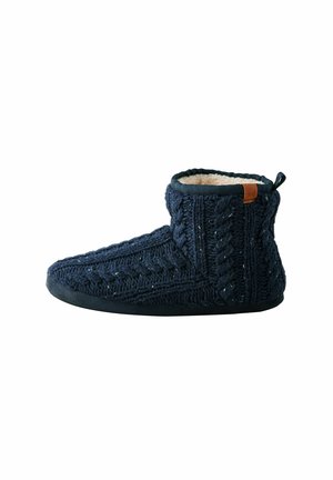 Navy blue knitted slipper with a cable pattern, soft fleece lining, and a black rubber sole. Features a brown leather accent on the back.
