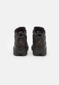 Svarta högprofilsneakers med en texturerad syntetöverdel, tonala snörstöden, en framträdande hällyft och guld "Air"-bokstäver bakpå.