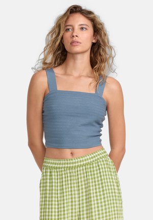 Cropped blue top with square neckline and wide straps, featuring textured ribbing. Paired with green and white gingham patterned skirt.