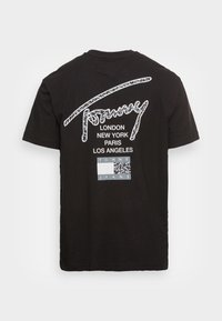 Svart bomulls t-shirt med vitt grafiskt text som visar stadnamn och en logotyp på baksidan, korta ärmar och rund halsringning.