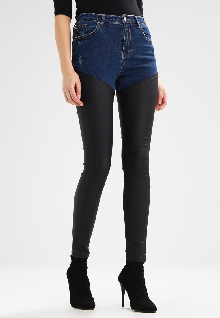 Pantalones de cintura alta que presentan una parte superior de denim con una parte inferior de cuero sintético negro, acentuados por un diseño geométrico de bloques de color y un ajuste slim.
