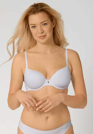 Reggiseno wireless grigio chiaro con design modellato e liscio e spalline regolabili. Presenta un piccolo accento metallico al centro.