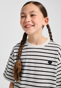 Randig t-shirt i ljusgrått och marinblått, med rund hals och korta ärmar. Särskild detalj: liten broderad logga på bröstet.