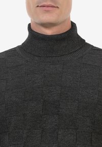 Dunkelgrauer Rollkragenpullover mit einem strukturierten, karodierten Muster und geripptem Kragen. Das Material wirkt weich und hat ein strukturiertes Design.