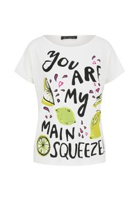 Biała koszulka z czarnym i zielonym nadrukiem oraz grafikami cytryny, o luźnym kroju i szerokim dekolcie. Napis brzmi: "Jesteś moją główną wyciskarką!"