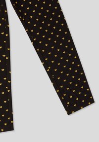 Leggings neri con un motivo ripetuto di piccoli cuori dorati, realizzati in un materiale morbido ed elastico. Texture liscia, forma aderente.