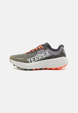 Zapatilla de running ligera en gris y oliva, con un sistema de cordones en color naranja, parte superior de malla transpirable y una gruesa suela intermedia blanca con una suela texturizada.