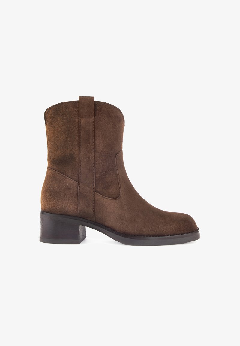 Botte cheville en suede marron avec un bout arrondi, des panneaux latéraux élastiques et un petit talon carré, présentant une texture lisse et un design simple.