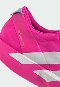 Rosa løpesko med teksturert overdel, med grå aksent ved hælen og hvite diagonale striper på sålen. "ADIZERO ADIOS 9" merkevare synlig.
