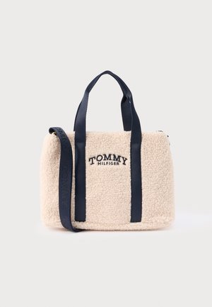 Borsa beige in finta pelliccia con manici in pelle blu navy e tracolla staccabile. Presenta il logo "TOMMY HILFIGER" impresso sul davanti.