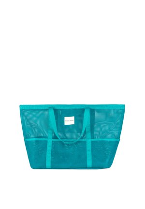 Bolso grande de malla turquesa con dos asas y una etiqueta rectangular blanca que dice "YSABEL MORA" en el centro frontal.