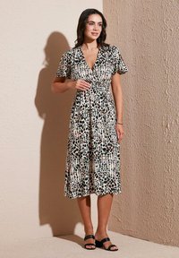 Short-sleeve wrap dress in a lightweight fabric featuring a multi-colored abstract pattern on a cream background, with a fitted waistline.