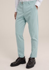 Light mint green trousers with a smooth texture, tapered fit, side pockets, and a front button closure, paired with black lace-up shoes.