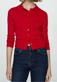 Rode cardigan met een kraag, lange mouwen en knoopsluiting. Gebreide textuur, aangesloten taille en geribde manchetten. Gekozen over donkere denim.