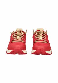 Un paio di scarpe da tennis rosse con lacci e suole beige, viste frontalmente su uno sfondo bianco.