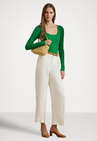 Πράσινο ριμπ μακρυμάνικο τοπ, εκρού παντελόνι φαρδιάς γραμμής, καφέ πλεκτή ζώνη, μικρή πλεκτή τσάντα και μπεζ ψηλοτάκουνα παπούτσια.