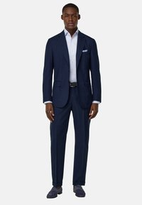 Costume bleu à rayures, design sur mesure, deux poches sur la veste, chemise habillée blanche, pochette carrée unie, et mocassins bleu navy.