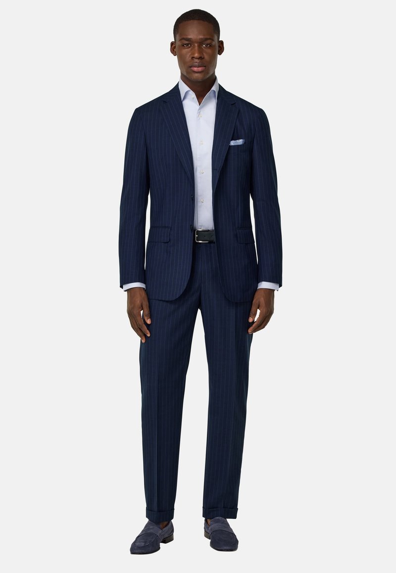 Costume bleu à rayures, design sur mesure, deux poches sur la veste, chemise habillée blanche, pochette carrée unie, et mocassins bleu navy.