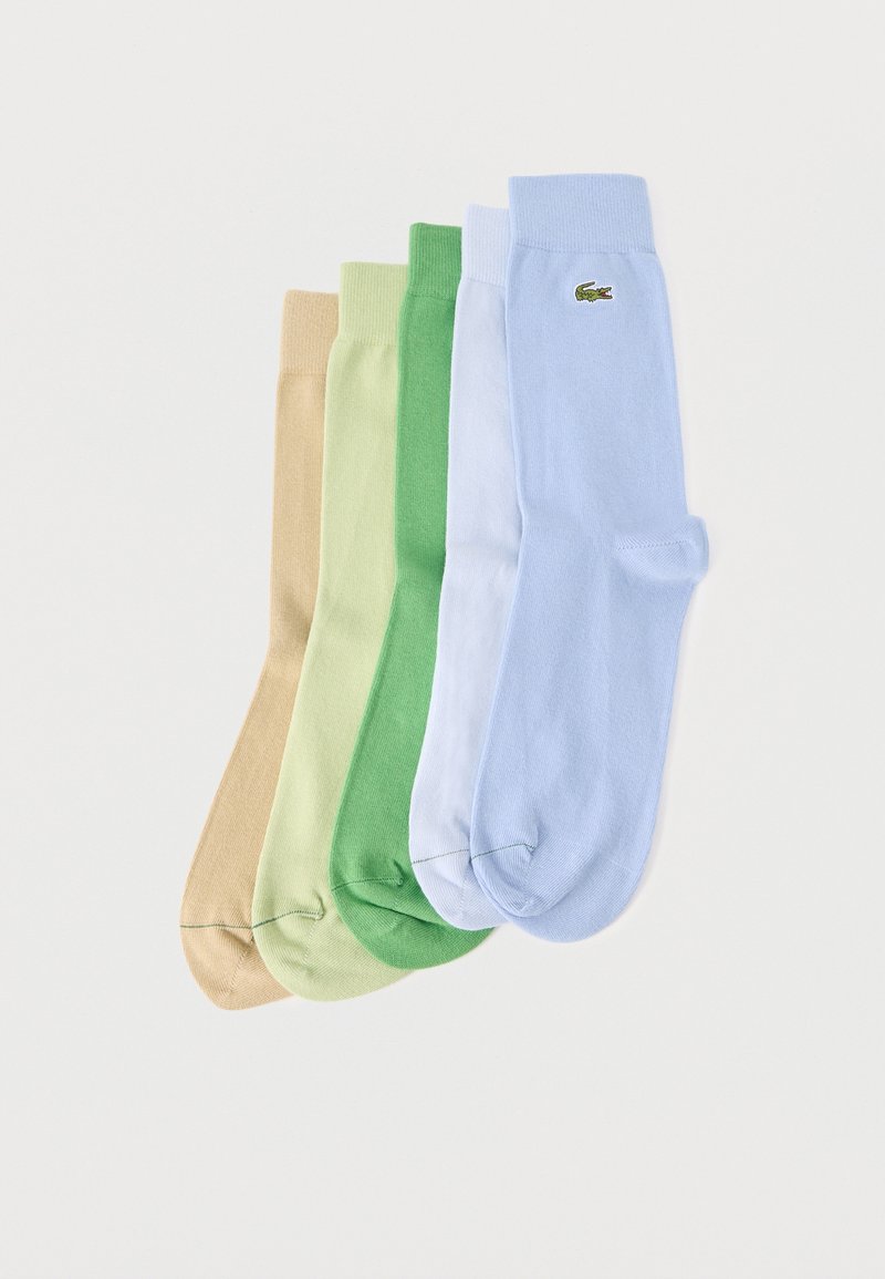 Cinq paires de chaussettes basses en beige, vert clair, vert, blanc, et bleu clair avec un petit logo crocodile vert sur la paire bleue.