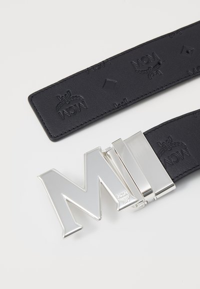 Black leather belt featuring embossed MCM logo pattern, silver metal "M" buckle, and sleek design with rectangular hardware accents.