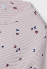 Tessuto rosa a coste con scollatura rotonda, caratterizzato da piccoli fiori ricamati in blu e viola sparsi qua e là.