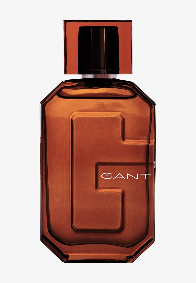 Brown glass perfume bottle with an octagonal shape, featuring a prominent "G" logo. The cap is black and square, with a glossy finish.