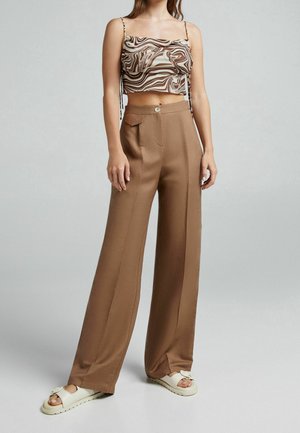Pantalon marron taille haute à jambes larges, associé à un crop top arborant un motif marbré marron et crème.
