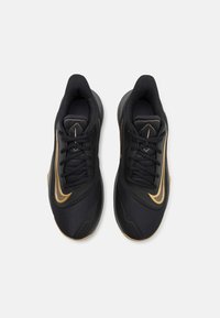 Czarne buty sportowe z teksturowaną cholewką, złotymi akcentami i okrągłym noskiem. Posiadają sznurowany design oraz wyściełany kołnierz.