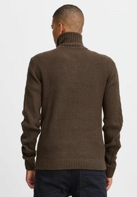 Suéter marrón de punto con un cuello alto, patrón texturizado, puños y dobladillo acanalados, y mangas largas. Costuras laterales detalladas.