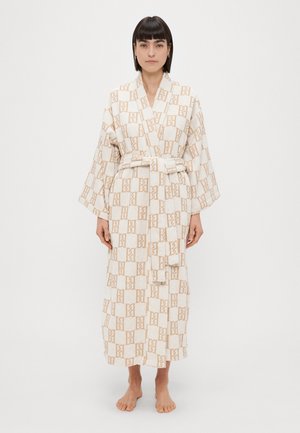 Valge ja beež triibuline vannituba, millel on sidumisvöö, laiad varrukad ja pehme tekstuur. Omab geomeetrilist mustrit üle kogu pinna.