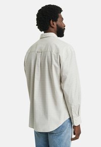 Lichtbeige geruit shirt met een rugplooi, button-down kraag en lange mouwen, aangevuld met een relaxte pasvorm en een zachte stoftextuur.