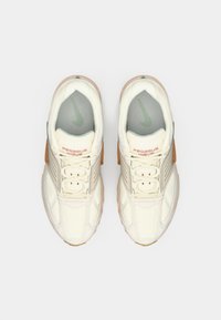 Off-white Nike Pegasus Wave sportcipő pár,5854f2არისხaztó dőn karkotóval és világos barna díszítéssel, felülnézetből, egyszínű háttérrel bemutatva.