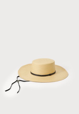 Stråhatt med bred skygge, naturlig beige farge, med et svart bånd og knytninger for sikker bruk. Jevn tekstur gjennom hele.