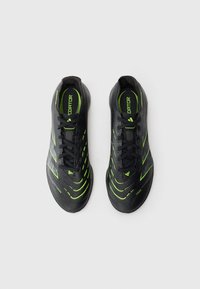 Une paire de crampons de football Adidas Predator noirs et verts vue de dessus sur un fond blanc.