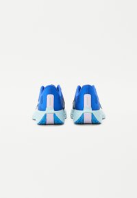 Blaue Sportschuhe mit strukturiertem Mesh-Obermaterial, kontrastierender hellblauer Sohle und pinken Akzenten an der Ferse. Abgerundetes Design mit ausgeprägtem Profil.