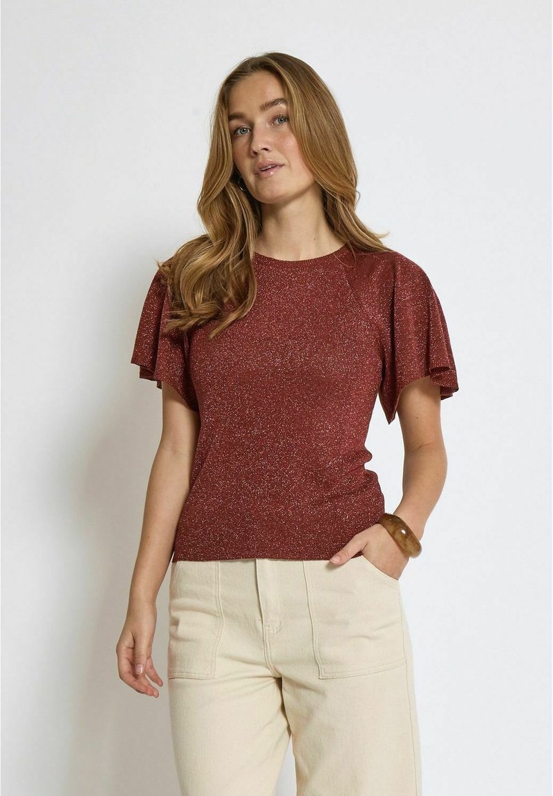 Burgundy short-sleeved top featuring shiny, textured fabric with ruffled sleeves. Paired with cream-colored, high-waisted pants.