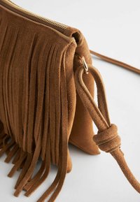 Borsa a tracolla in suede marrone con dettagli a frange, chiusura con zip e tracolla annodata. Caratterizzata da una texture morbida e un design compatto.