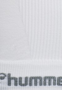 Weißer gerippter Stoff mit einem grauen Logo am unteren Ende. Die Textur ist glatt mit feinen vertikalen Linien und einem subtilen Glanz.