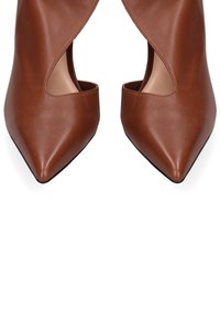 Bruine leren pumps met een spitse neus en openingen aan de zijkant. Glad oppervlak, minimalistisch ontwerp en een slanke, taps toelopende silhouet.