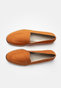 Orange slip-on skor i slät läder, med rund tå, sömnadsdetaljer och en subtil metallackent på sulan.