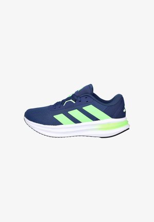 Zapatillas deportivas azul marino con detalles en verde, parte superior de malla, entresuela blanca acolchada y suela exterior de goma negra con un patrón texturizado.