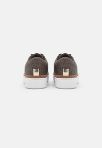 Sneaker marroni con motivo, suola spessa bianca e dettagli dorati, visibili da dietro su uno sfondo bianco.