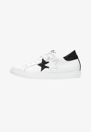 Sneakers bianchi in pelle con due stelle in bianco e nero, accentuazione in pelle nera texturizzata sul tallone e punta rotonda. Chiusura con lacci e suola in gomma.