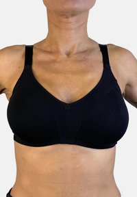 Sujetador negro sin costuras con un escote en forma de V, tirantes ajustables y detalles florales en las uniones de los tirantes. Tela suave y elástica.