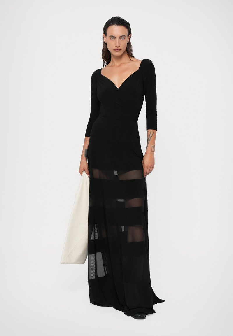 Black long-sleeve dress with a fitted bodice and sheer striped skirt. Soft fabric with a plunging neckline and flowing design.