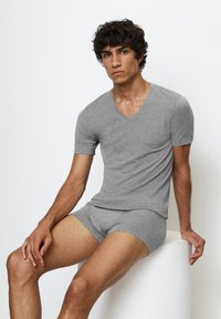 Grijze katoenen T-shirt met een V-hals en korte mouwen, gecombineerd met bijpassende boxershorts. Gladde textuur, eenvoudig ontwerp, aansluitende pasvorm.