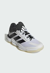 Chaussure de sport blanche et noire avec tige en mesh, trois rayures noires, détails texturés et semelle en caoutchouc. Comprend un col rembourré et des lacets.